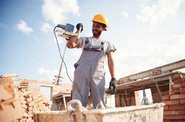 Betonu karıştırmak için bir aletle. Yakışıklı Hintli adam şantiyede..