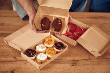 Yemek masanın üstünde. İnsan, ekolojik kutulardaki lezzetli tatlılarla birlikte. Kapalı mekanda durmak.