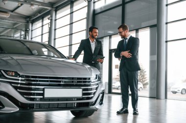 Otomobilden bahsediyoruz. Adam galeride müşteriye danışıyor..