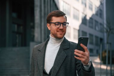 Güzel güneş ışığı. Resmi kıyafetli yakışıklı dışarıda, iş binasının yanında..