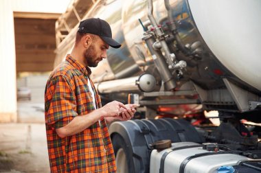 Akıllı telefonu tutuyorsun. Gündelik giysiler içindeki genç kamyon şoförü..