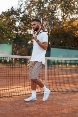 Raket ve topla. Genç adam güneşli bir günde tenis kortunda..