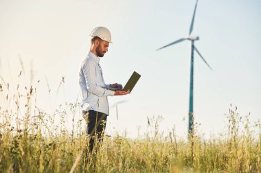 Dizüstü bilgisayarla çalışıyor. Servis mühendisi yel değirmenleriyle sahada..