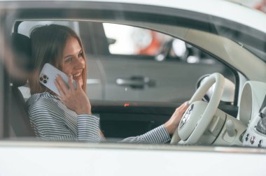 İçeride oturup telefonla konuşuyorlar. Güzel kadın modern arabasıyla içeride..