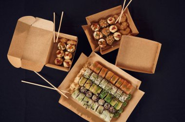 Masadaki kağıt eko kutuların içindeki suşi rulolarının üst görüntüsü..