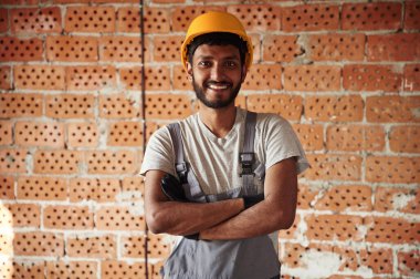 İçeride, tuğladan duvara karşı. Yakışıklı Hintli adam şantiyede..