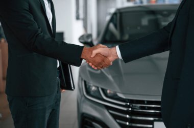 Manzarayı kapat. İki işadamı araba galerisinde el sıkışıyorlar..