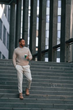 Elde iç. Yakışıklı siyah adam iş binasının yakınında dışarıda..