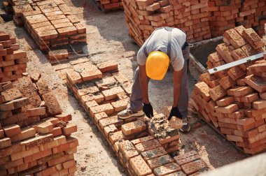 Binanın tepesinde tuğlalarla. Yakışıklı Hintli adam şantiyede..