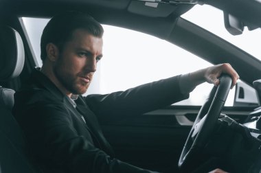 Ciddi bir yüz ifadesi. Arabayı sürüyorum. Resmi iş elbiseli adam modern otomobilde oturuyor..