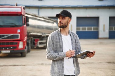 Müdür not defteriyle birlikte. Gündelik giysiler içindeki genç kamyon şoförü..