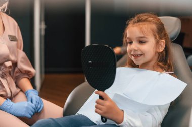 Bayan doktor küçük bir kızla çalışıyor. Stomatolojik dolapta..