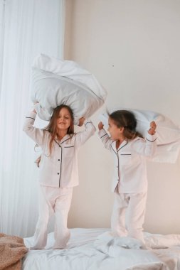 Yastık savaşı oynuyoruz. İki küçük kız yurt odasında birlikte eğleniyorlar..