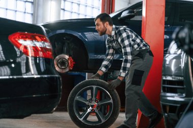 Yan görüş. Arabanın lastiğini hareket ettiriyorum. Üniformalı adam araba galerisinde çalışıyor..