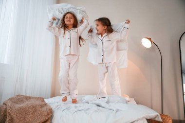 Yurt içi odada, yatağın üstünde. Yastık savaşı oynuyoruz. İki küçük kız yurt odasında birlikte eğleniyorlar..