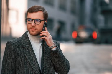 Resmi giyinmiş yakışıklı bir adamın portresi iş binasının yakınındadır..