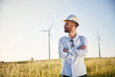 Yakışıklı servis mühendisi sahada yel değirmenleriyle duruyor..