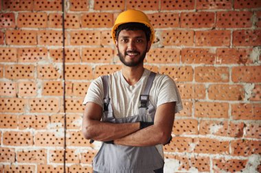 İçeride, tuğladan duvara karşı. Yakışıklı Hintli adam şantiyede..