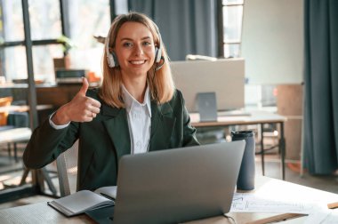 Resmi giyinmiş genç bir bayan ofiste çalışıyor..