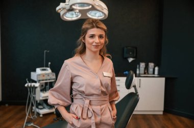 Doktor ayakta ve gülümsüyor. Stomatolojik dolapta..