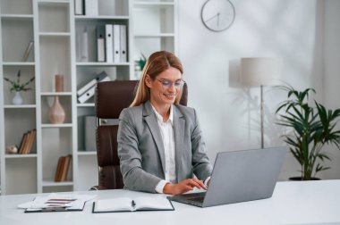 Laptop kullanıyorum. İş kadını resmi giysileri ofiste çalışıyor..