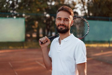 Pozitif genç adam güneşli bir günde tenis kortunda. raketi tut.