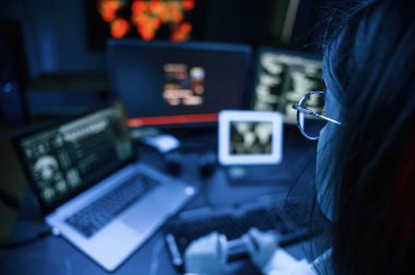 Genç profesyonel bilgisayar korsanı bilgisayar başında ve ekranlar hakkında çok fazla bilgiye sahip..