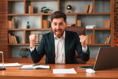 Başarıyı kutluyoruz. Resmi kıyafetli bir iş adamı içeride çalışıyor..