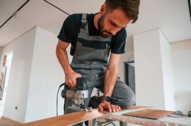 Masanın üzerinde. Matkapla tahta kesiyorum. Adam yeni kaplamalı ahşap döşeme kuruyor..
