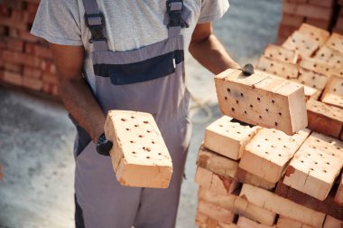 Ellerinde tuğlayla. İnşaat alanında çalışan adamın yakın görüntüsü..