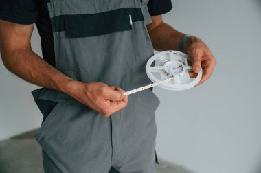 Parçayı diyotlarla tutuyorum. Adam iç mekanda ışıklandırma ekipmanlarıyla çalışıyor..