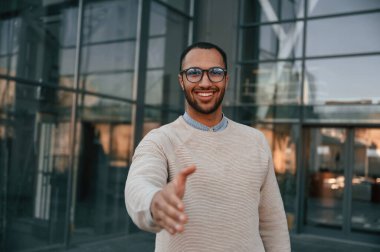 Selamlama eli uzatıyorum. Yakışıklı siyah adam iş binasının yakınında dışarıda..