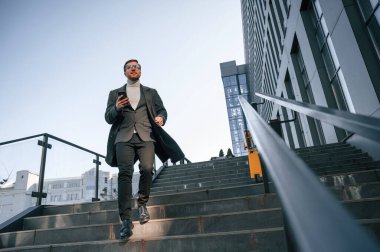 Merdivenlerde. Resmi kıyafetli yakışıklı dışarıda, iş binasının yanında..