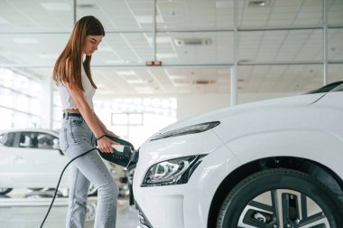 Yan görüş. Aracı şarj ediyorum. Güzel kadın modern arabasıyla içeride..