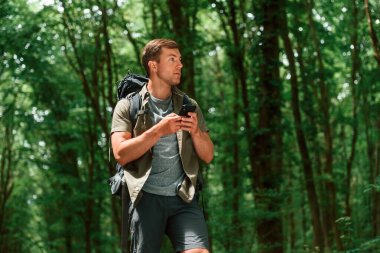 Navigasyon için akıllı telefonla yolu arıyorum. Yaz ormanında bir turist. Keşif ve eğlence kavramı.