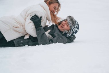 Güzel bir çift karda uzanıyor ve birbirlerine sarılıyorlar. Aşk kavramı. Kış mevsimi.