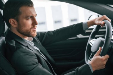 Test sürüşü. Resmi iş elbiseli adam modern otomobilde oturuyor..