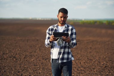 Siyah renkli dijital tablet ellerinde. Tarım tarlasında. Yakışıklı Hintli adam..