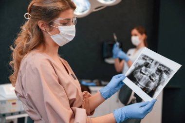 Doktorlar evdeler. Tutan ve röntgene bakan kadın. Stomatolojik dolapta..