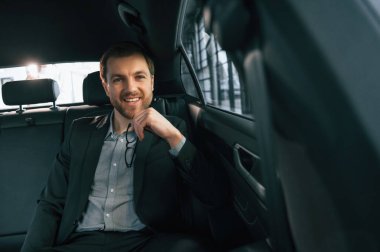 Rahat modern bir otomobilde. Resmi iş elbiseli adam..