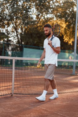 Raket ve topla. Genç adam güneşli bir günde tenis kortunda..