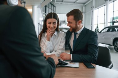 Aile yeni bir araba satın alıyor. Araba galerisinde üç kişi birlikte çalışıyor..