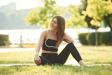 Siyah spor kıyafetlerle. Güzel genç bayan güneşli bir günde parkta..