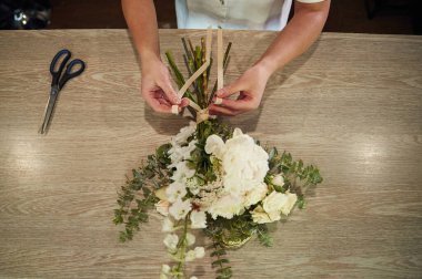 Dükkanda çiçeklerle çalışan kadının yakın görüntüsü..