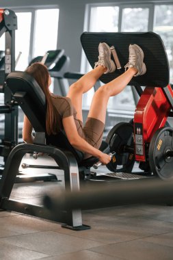 Bacaklar için egzersiz yapıyorum. Spor vücut yapısı olan güzel bir kadın spor salonunda..