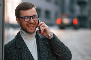 Resmi giyinmiş yakışıklı bir adamın portresi iş binasının yakınındadır..