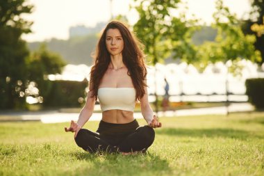 Lotus pozunda meditasyon. Spor elbiseli güzel bir kadın güneşli bir günde parkta..