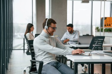 Telefonum çalıyor. Kulaklıkla. Erkekler ve kadınlar ofiste birlikte çalışıyorlar..