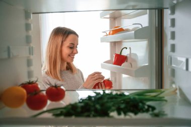 Buzdolabından sebzeleri alıyorum. Güzel genç bayan mutfakta..