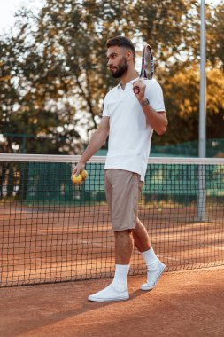 Raket ve topla. Genç adam güneşli bir günde tenis kortunda..